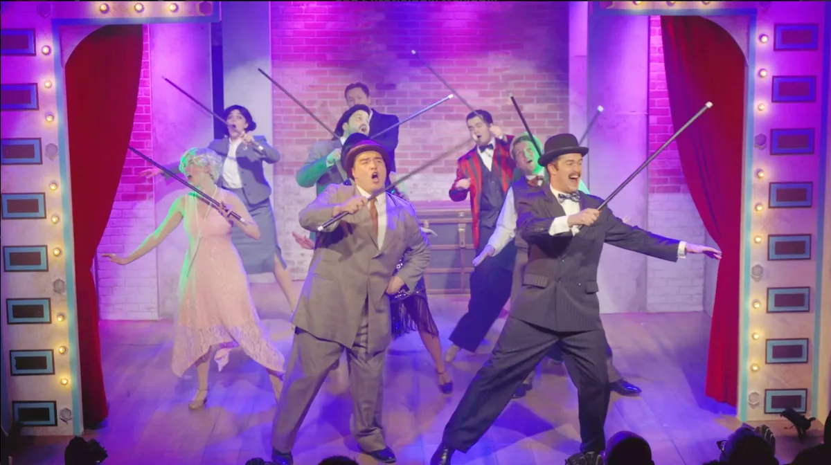The cast of Lefty and Crabbe on stage mid-number, canes raised, under purple and amber stage light